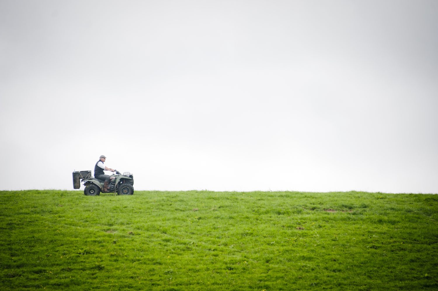 dairy farmer inspecting his grass fields on a quad bike.